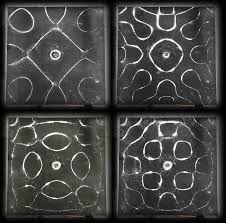 A two-by-two grid of four modern Chladni plate photographs, each showing a different symmetric nodal pattern formed by light-colored particles on a dark vibrating metal surface.